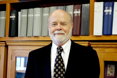 William Woodall, a professor of statistics, poses in front of a bookcase 